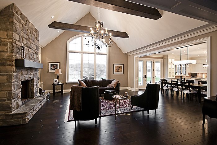 Renovated great room with a stone fireplace and exposed timber beams